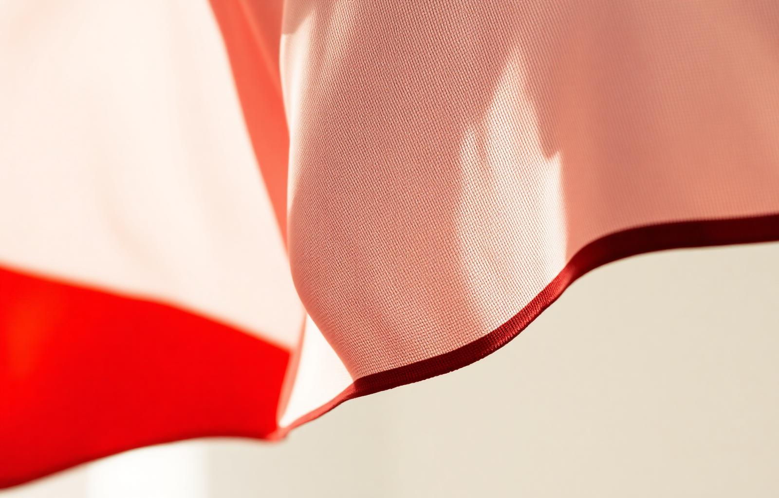 Soft folds of red and white flag fabric in natural light